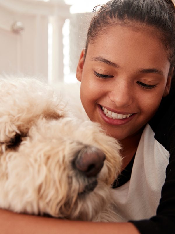 young-teen-girl-embracing-pet-dog-on-her-bed-PGQHKBW.jpg